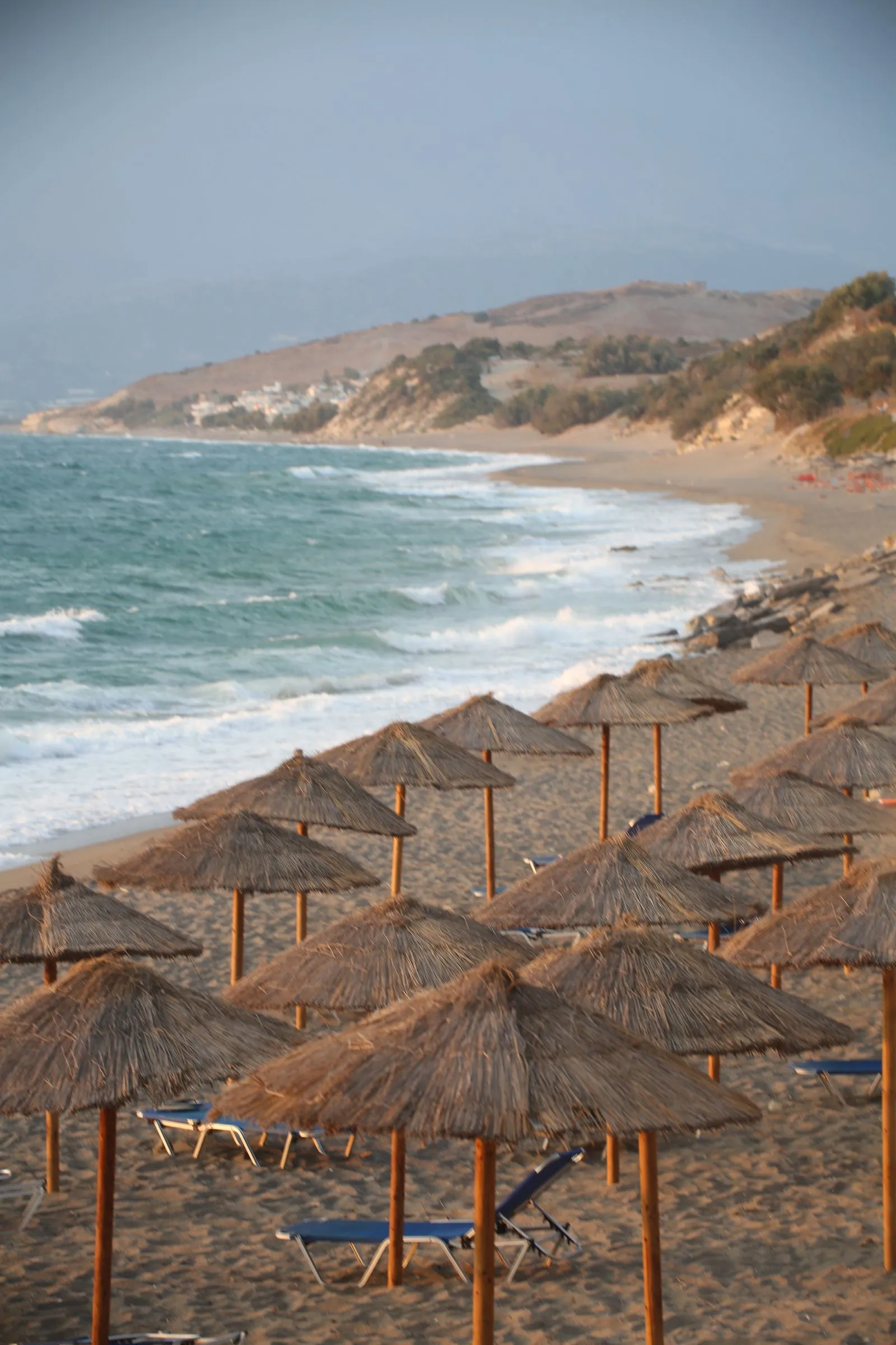 Playa mediterránea llena de sombrillas de paja junto al mar